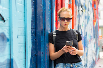 Image showing Woman using smartphone against colorful graffiti wall in New York city, USA.