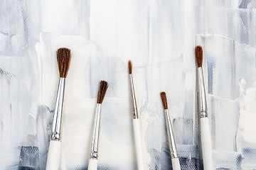 Image showing New paint brushes on black and white canvas