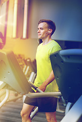 Image showing man with smartphone exercising on treadmill in gym