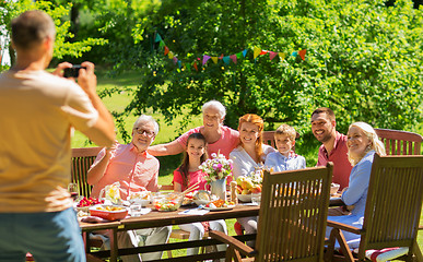 Image showing happy family photographing at dinner in garden