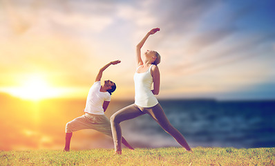 Image showing couple making yoga warrior pose outdoors