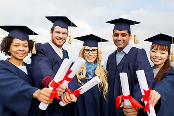 Image showing happy students in mortar boards with diplomas