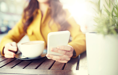 Image showing close up of woman texting on smartphone at cafe