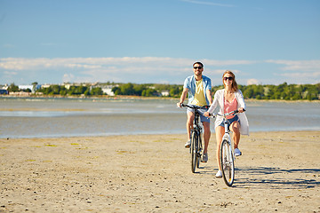 Image showing happy young couple riding bicycles at seaside