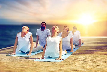 Image showing group of people doing cobra pose outdoors