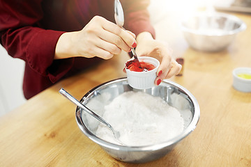 Image showing chef hands adding food color into bowl with flour