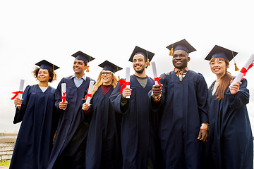 Image showing happy students in mortar boards with diplomas