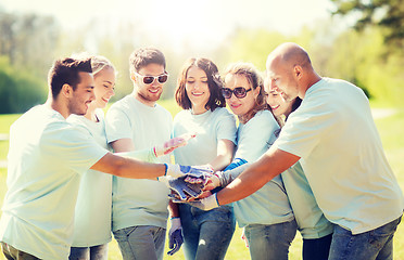 Image showing group of volunteers putting hands on top in park