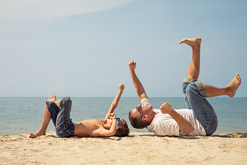 Image showing Father and son playing on the beach at the day time.