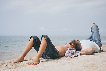 Image showing Father and son playing on the beach at the day time.