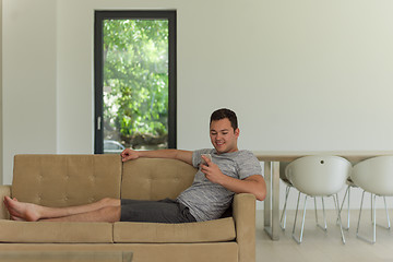 Image showing young man using a mobile phone  at home