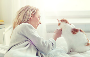 Image showing happy young woman with cat in bed at home