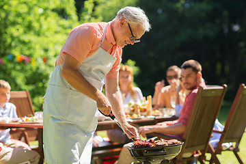 Image showing senior man cooking meat on barbecue grill outdoors