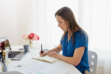 Image showing woman writing to notebook at office