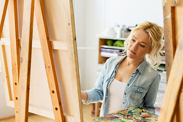 Image showing woman with easel painting at art school studio