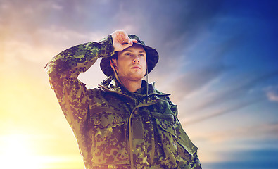 Image showing young soldier in military uniform over sky 