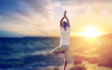 Image showing happy man making yoga tree pose over sea