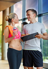 Image showing smiling young woman with personal trainer in gym