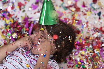 Image showing kid blowing confetti while lying on the floor