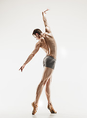 Image showing Athletic ballet dancer in a perfect shape performing over the grey background.