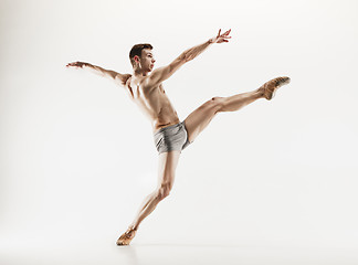 Image showing Athletic ballet dancer in a perfect shape performing over the grey background.