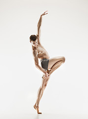 Image showing Athletic ballet dancer in a perfect shape performing over the grey background.