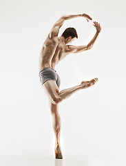 Image showing Athletic ballet dancer in a perfect shape performing over the grey background.