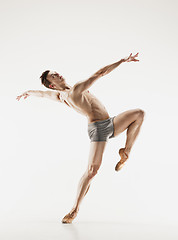 Image showing Athletic ballet dancer in a perfect shape performing over the grey background.