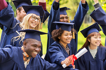 Image showing happy students in mortar boards with diplomas