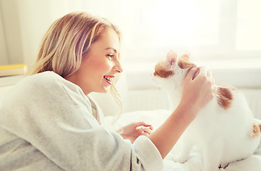 Image showing happy young woman with cat in bed at home