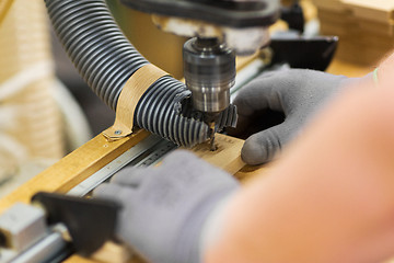 Image showing carpenter with drill press and board at workshop