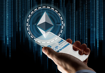 Image showing hand with smartphone and ethereum hologram