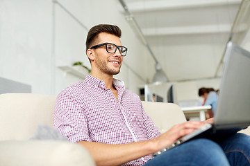 Image showing smiling man with laptop working at office