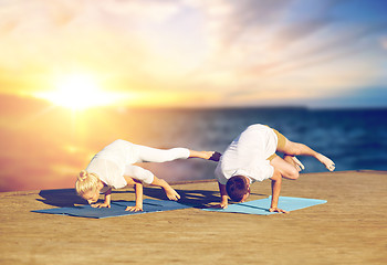 Image showing couple doing yoga side crane pose outdoors