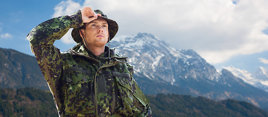 Image showing young soldier in military uniform over mountains