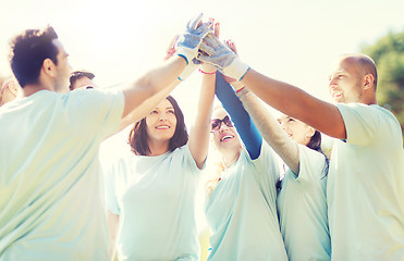 Image showing group of volunteers making high five in park