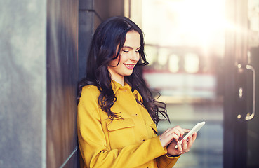 Image showing smiling young woman or girl texting on smartphone