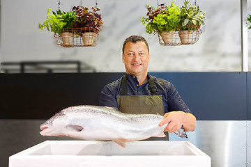 Image showing happy male seller holding trout at fish shop