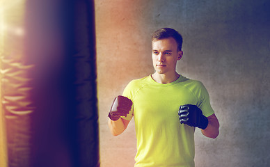 Image showing young man in gloves boxing with punching bag