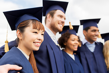 Image showing happy students or bachelors in mortar boards