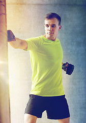 Image showing young man in gloves boxing with punching bag