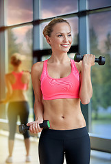 Image showing young sporty woman with dumbbells flexing biceps