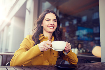 Image showing happy woman drinking cocoa at city street cafe