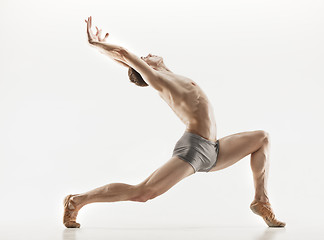 Image showing Athletic ballet dancer in a perfect shape performing over the grey background.