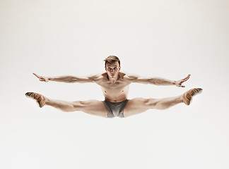 Image showing Athletic ballet dancer in a perfect shape performing over the grey background.