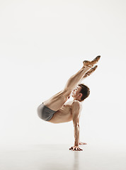 Image showing Athletic ballet dancer in a perfect shape performing over the grey background.