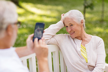 Image showing old woman photographing man by smartphone in park