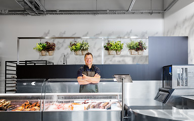 Image showing male seller with seafood at fish shop fridge