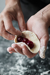 Image showing Woman cook manually sculpts dumplings stuffed with cherries