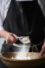 Image showing Female hands sifting flour to bowl.